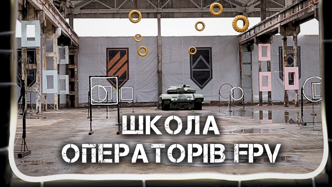 группа студентов с пультами управления дронами на учебном полигоне, инструктор показывает экран планшета